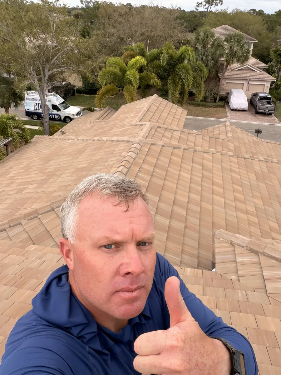 Adam, owner of AquaFlow Pro Wash, on a clean tile roof
