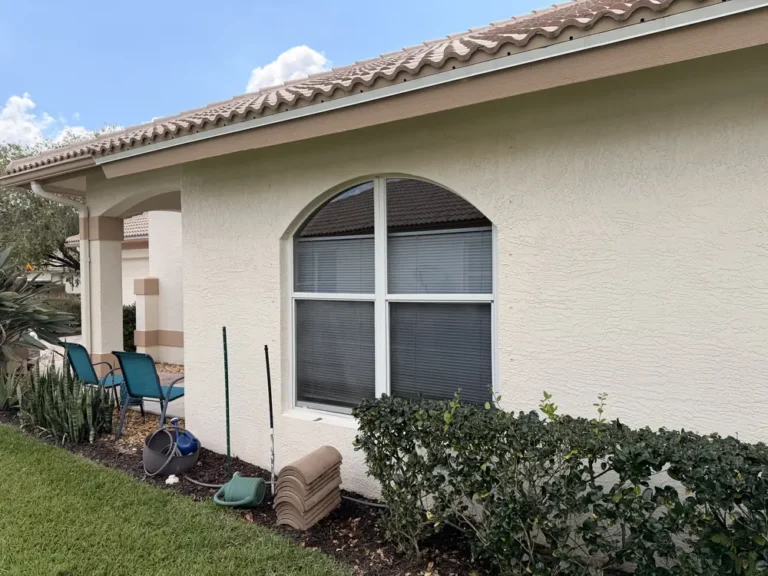 Clean white stucco home with arched window and landscaping in Port St. Lucie