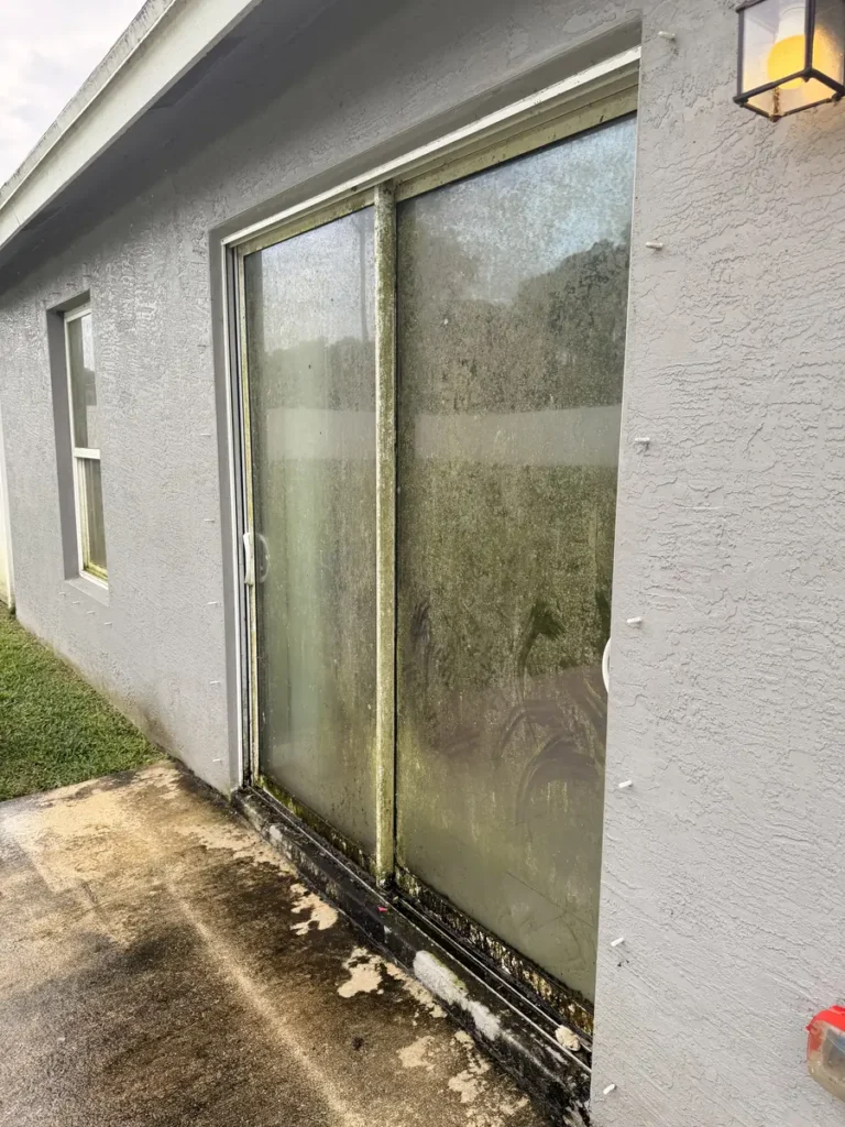 Sliding glass door with dirt and buildup on the glass, frame and track on a Port St. Lucie home